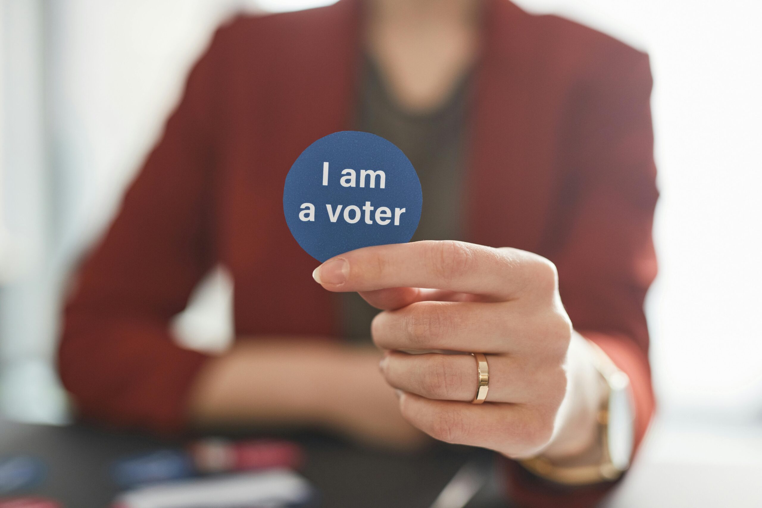 A person holds a voter badge, symbolizing civic responsibility and participation.